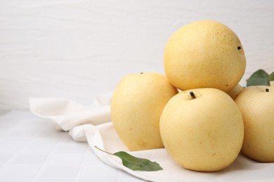 Photo of Delicious fresh apple pears on white tiled table, closeup. Space for text