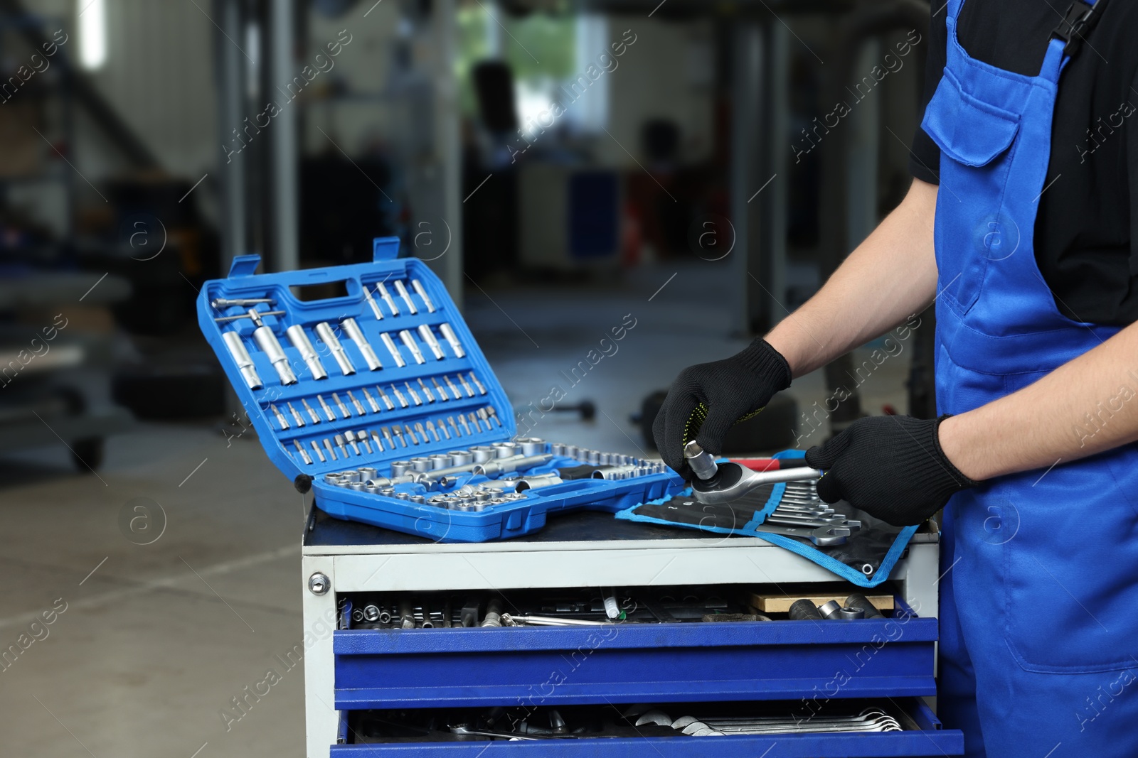 Photo of Auto mechanic with different tools at automobile repair shop, closeup