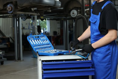 Photo of Auto mechanic with different tools at automobile repair shop, closeup