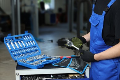 Auto mechanic with different tools at automobile repair shop, closeup