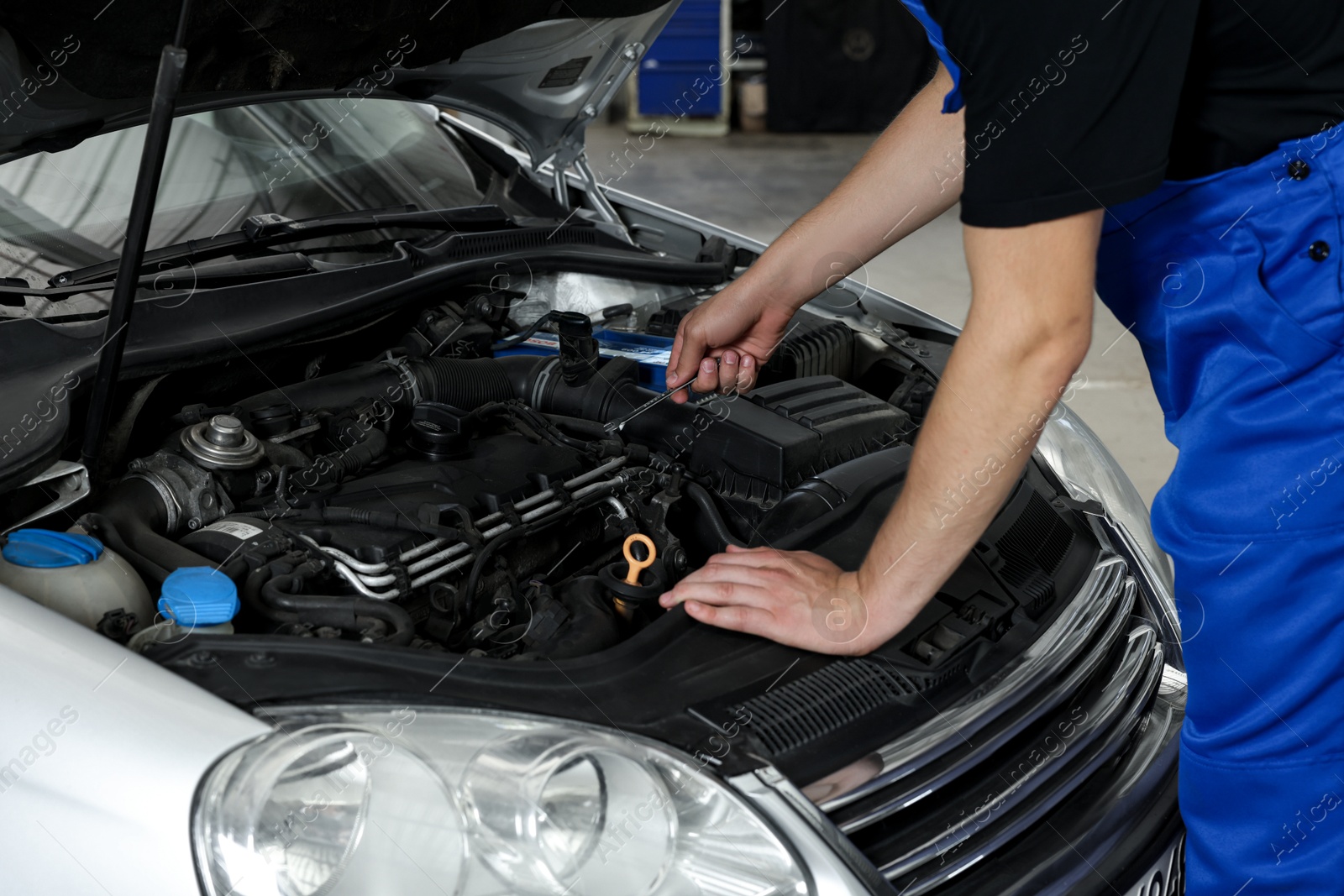 Photo of Auto mechanic fixing car at automobile repair shop, closeup