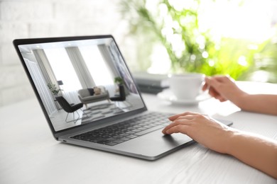 Image of Woman looking for house on real estate market website at table, closeup