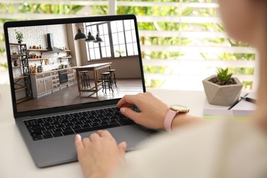 Image of Woman looking for house on real estate market website at table, closeup