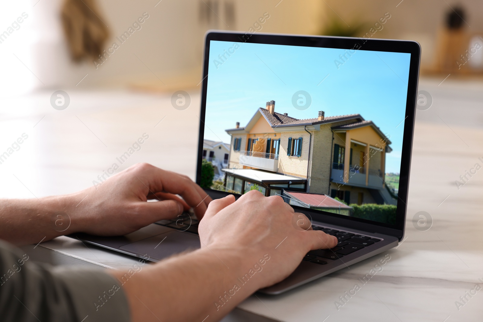 Image of Man looking for house on real estate market website at table, closeup