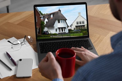 Man looking for house on real estate market website at table, closeup