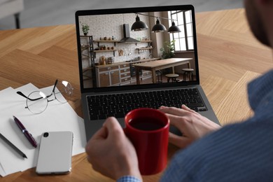 Image of Man looking for house on real estate market website at table, closeup