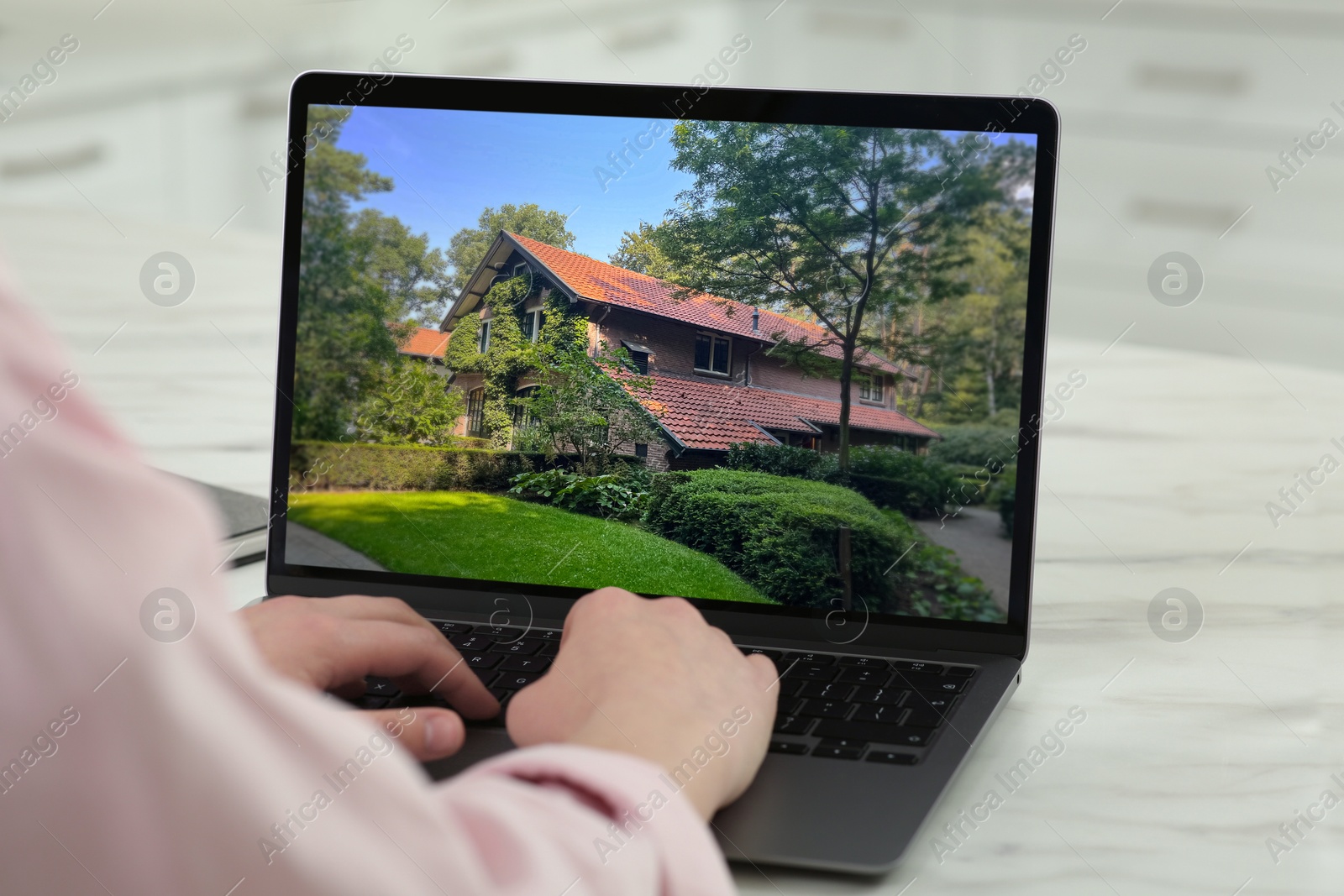 Image of Woman looking for house on real estate market website at table, closeup