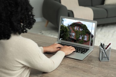 Woman looking for house on real estate market website at table, closeup