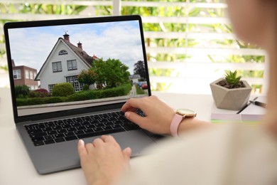 Woman looking for house on real estate market website at table, closeup