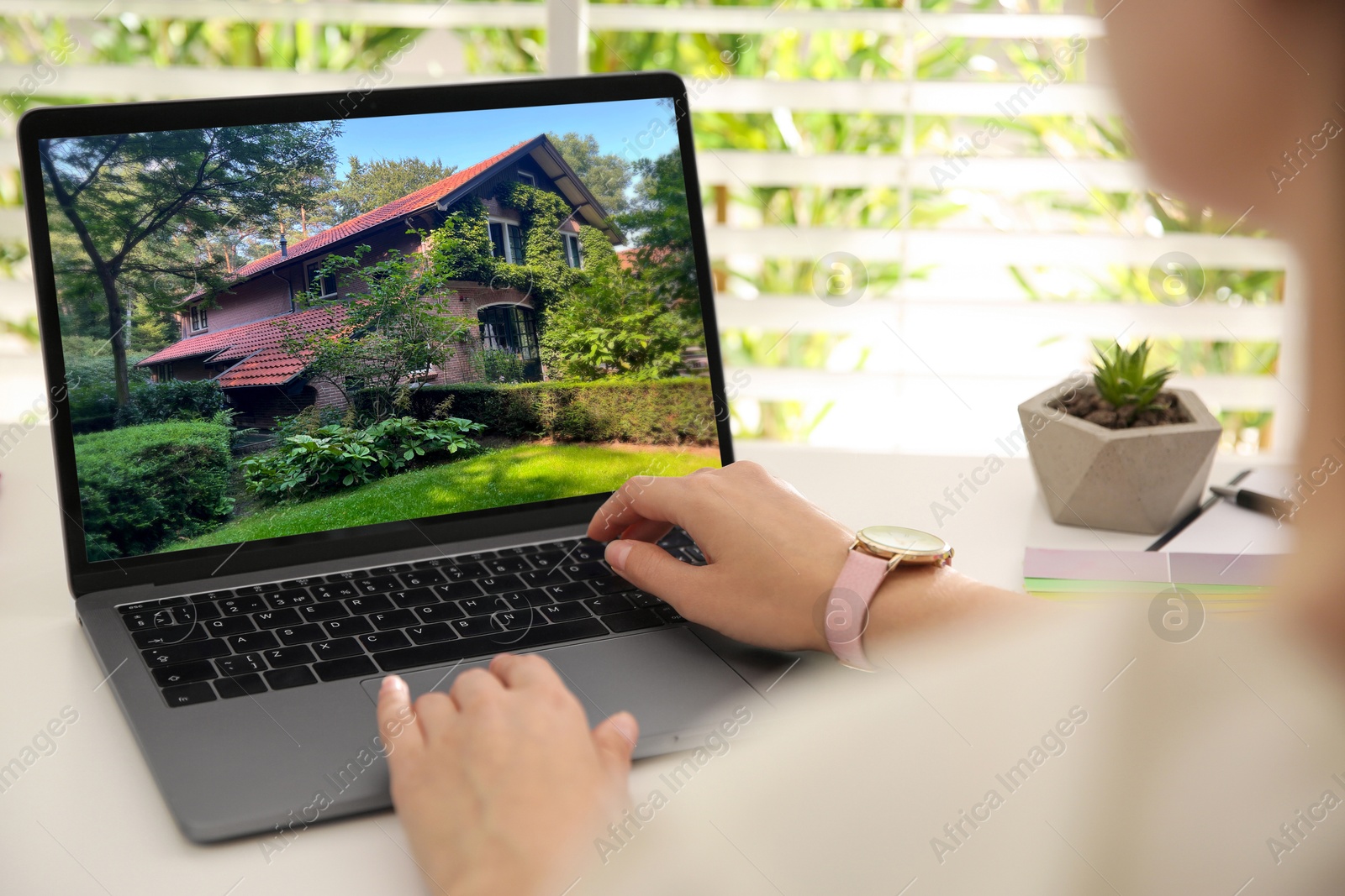 Image of Woman looking for house on real estate market website at table, closeup