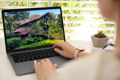 Image of Woman looking for house on real estate market website at table, closeup