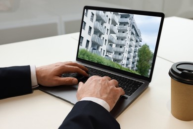 Man looking for house on real estate market website at table, closeup