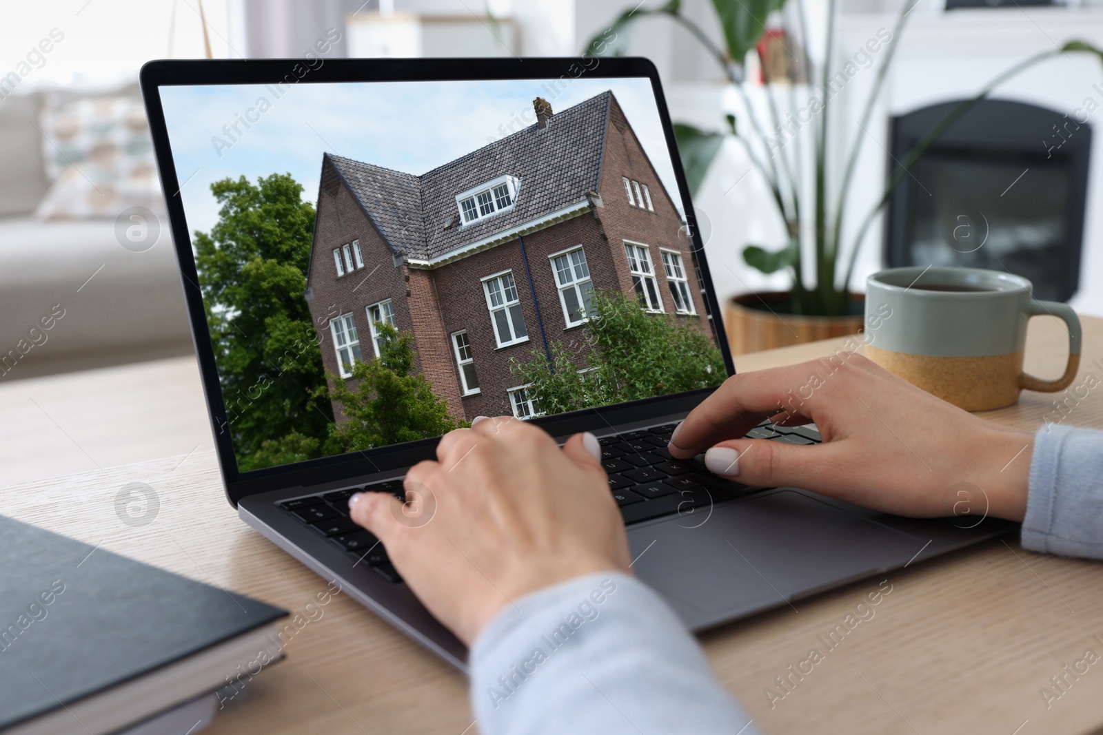 Image of Woman looking for house on real estate market website at table, closeup