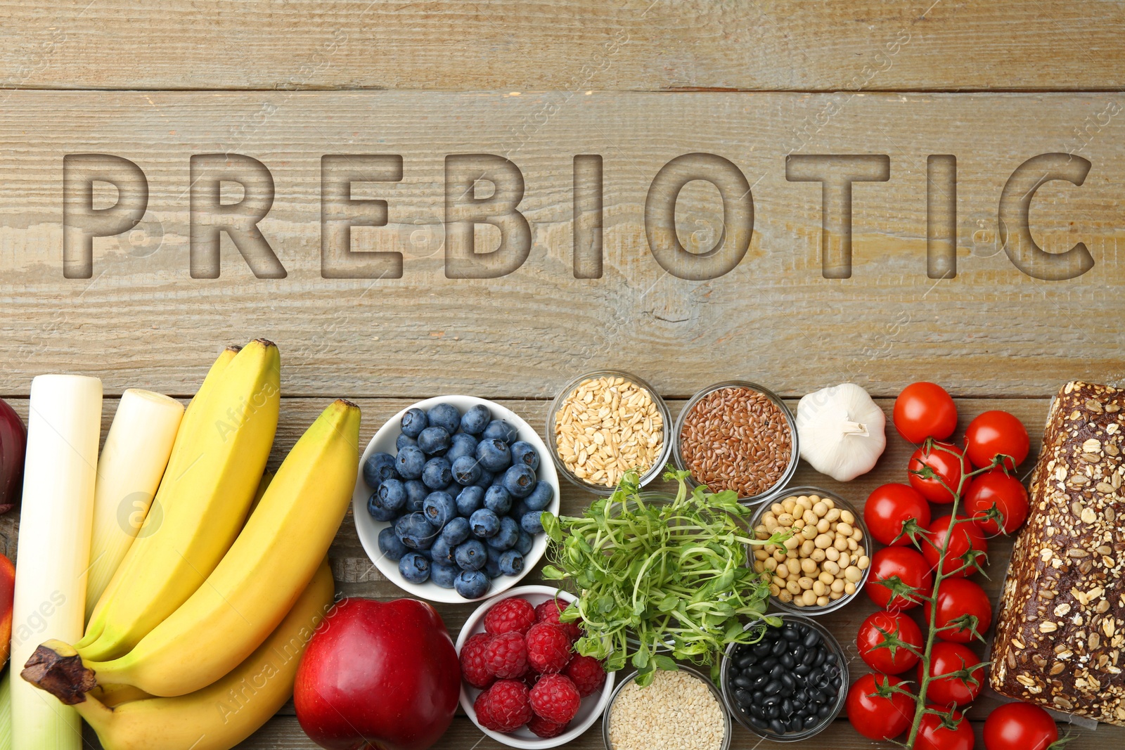 Image of Word Prebiotic and different gut-healthy foods on wooden table, top view