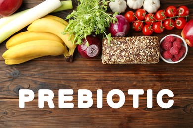 Image of Word Prebiotic and different gut-healthy foods on wooden table, top view