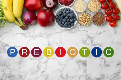 Image of Word Prebiotic and different gut-healthy foods on white marble table, top view