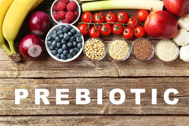 Image of Word Prebiotic and different gut-healthy foods on wooden table, top view