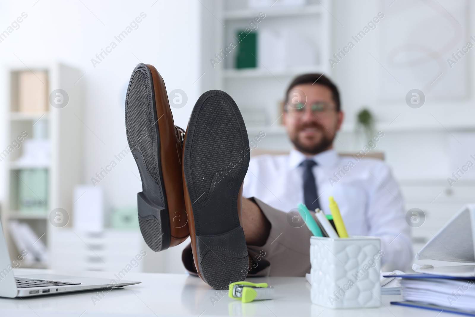 Photo of Businessman holding legs on table in office, selective focus. Break time