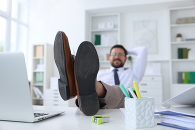 Photo of Businessman holding legs on table in office, selective focus. Break time