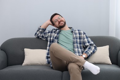 Photo of Smiling man relaxing on sofa at home