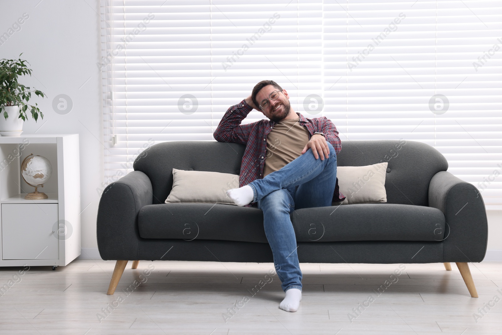 Photo of Smiling man relaxing on sofa at home