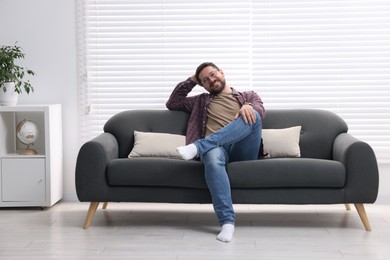 Smiling man relaxing on sofa at home