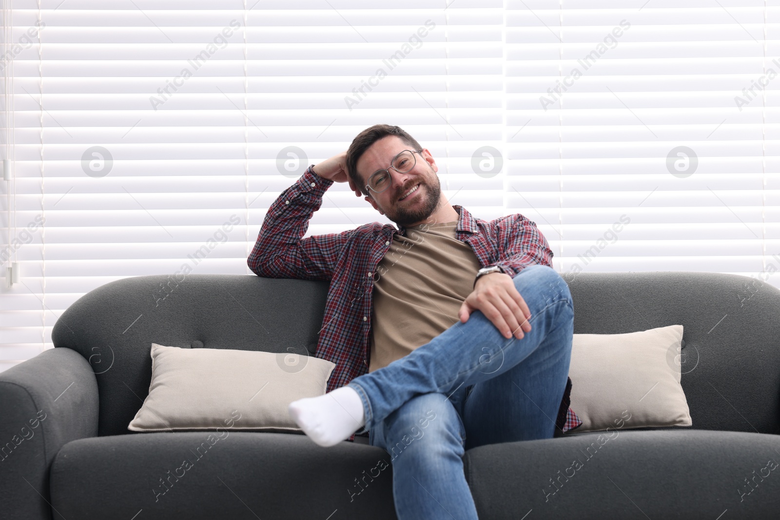 Photo of Smiling man relaxing on sofa at home