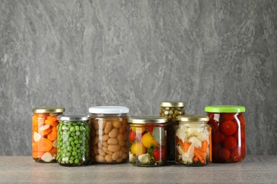 Photo of Different pickled products in jars on wooden table