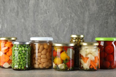 Photo of Different pickled products in jars on wooden table