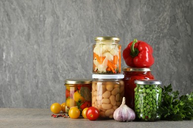 Photo of Different pickled products in jars on wooden table