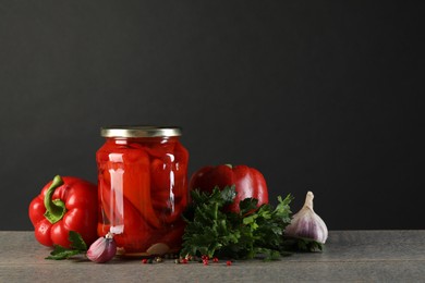 Photo of Tasty pickled vegetables in jar and fresh ingredients on wooden table. Space for text