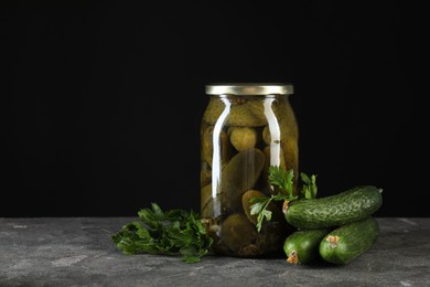 Photo of Tasty pickled cucumbers in jar and fresh ingredients on grey textured table, space for text