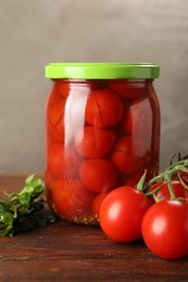 Photo of Tasty pickled tomatoes in jar and fresh ingredients on wooden table, closeup