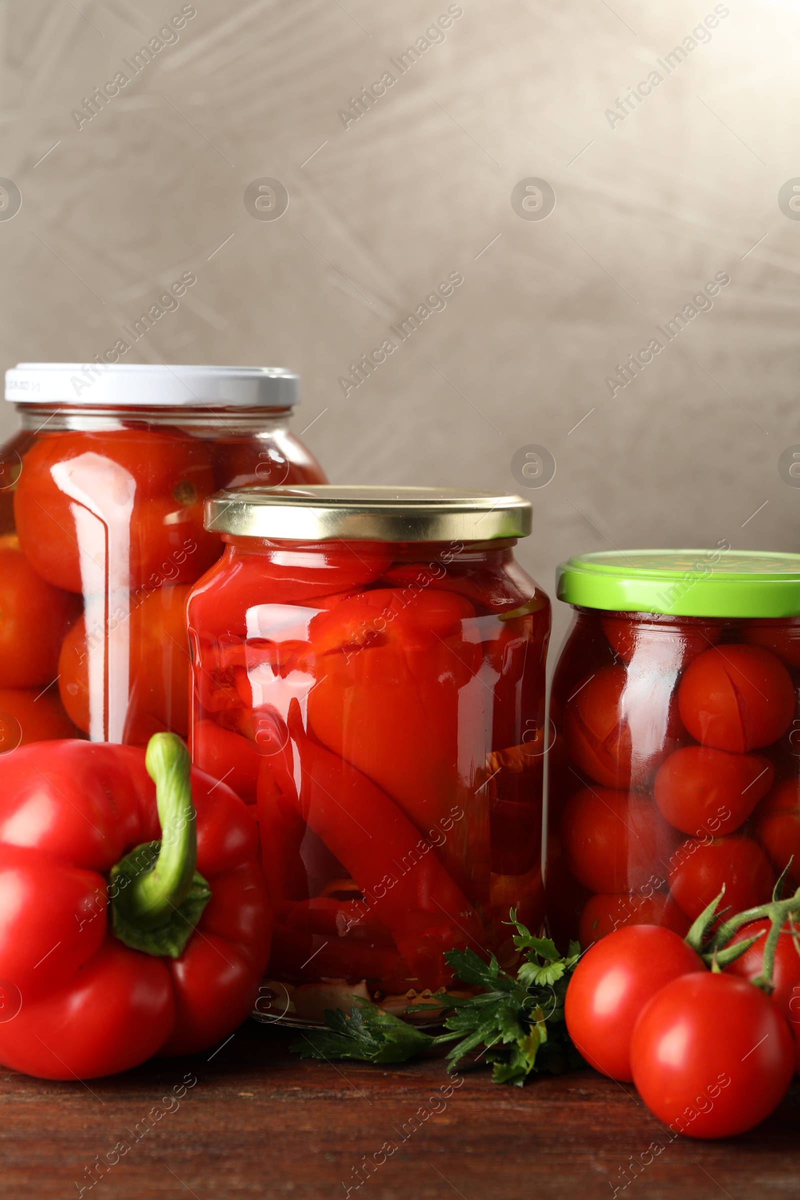 Photo of Different pickled vegetables in jars and fresh ingredients on wooden table