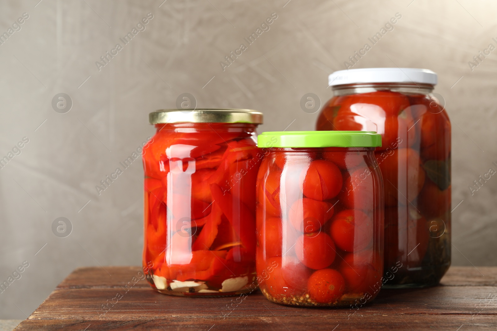 Photo of Different pickled vegetables in jars on wooden table