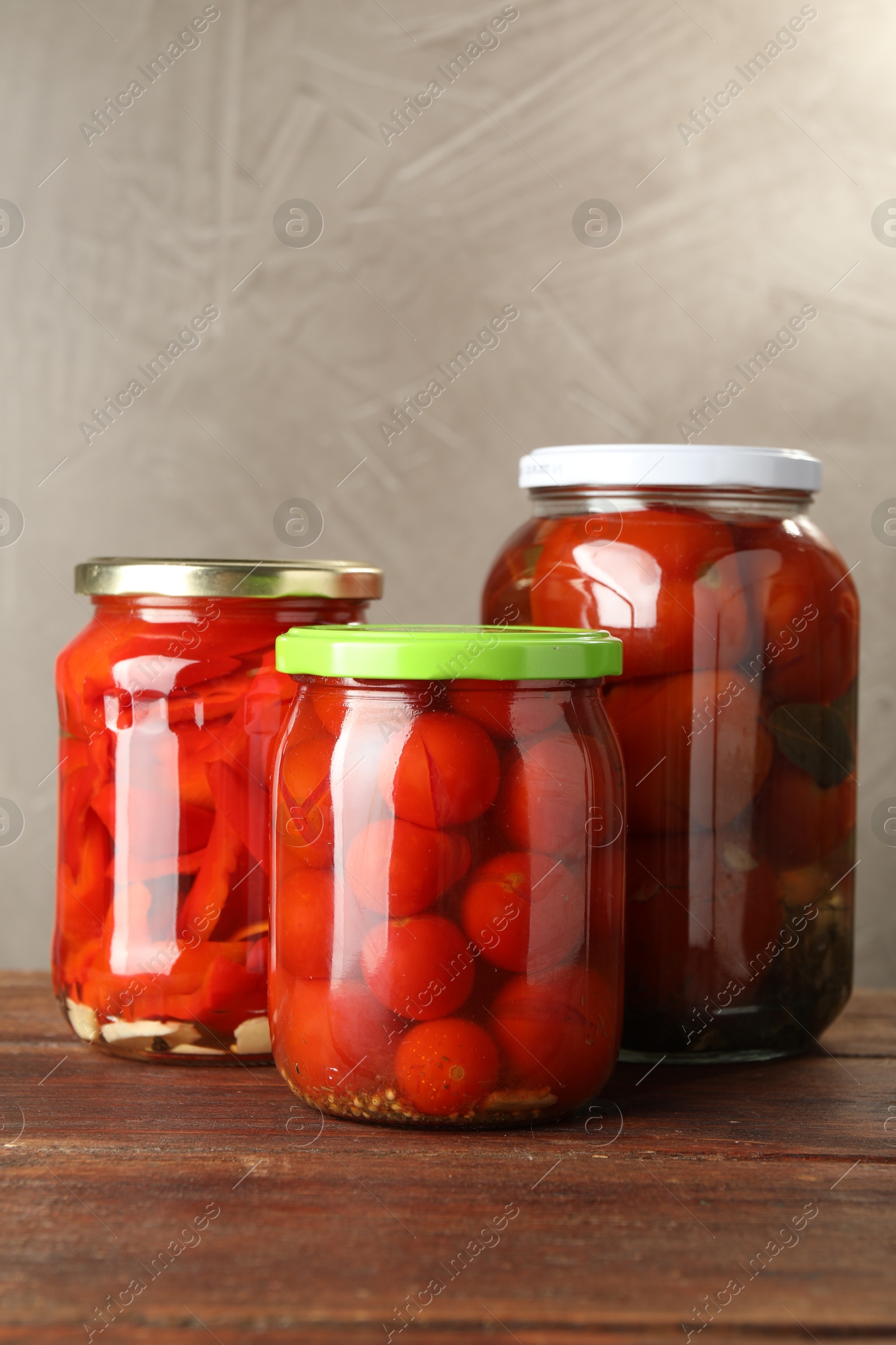 Photo of Different pickled vegetables in jars on wooden table