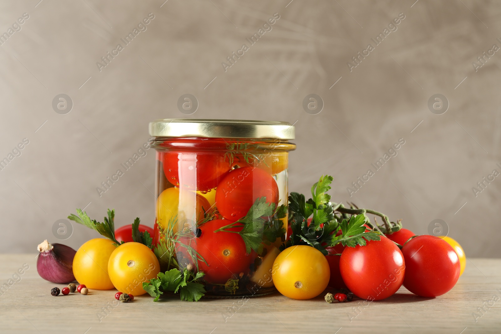 Photo of Different pickled tomatoes in jar and fresh ingredients on wooden table