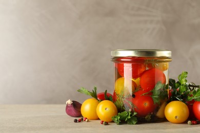 Photo of Different pickled tomatoes in jar and fresh ingredients on wooden table, space for text