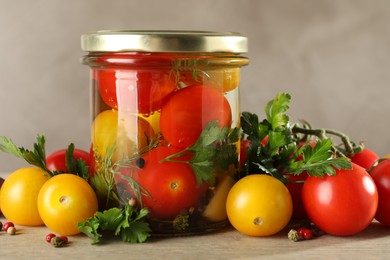 Photo of Different pickled tomatoes in jar and fresh ingredients on wooden table, closeup