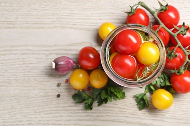 Photo of Different pickled tomatoes in jar and fresh ingredients on wooden table, flat lay