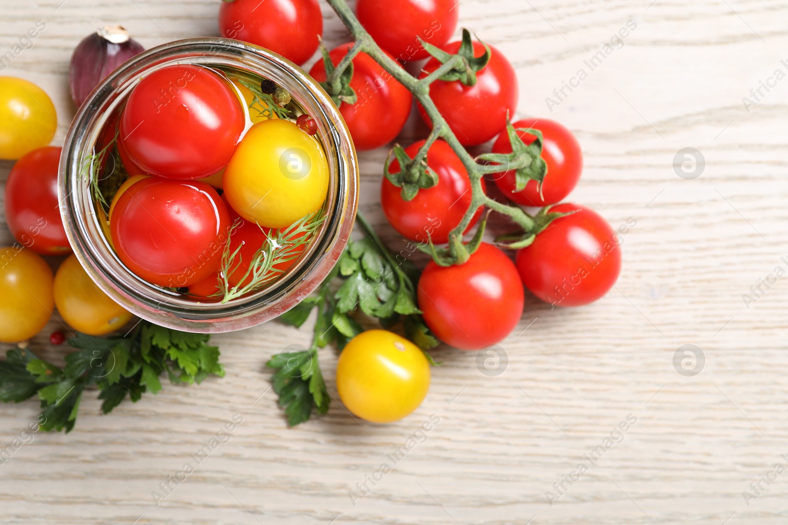 Photo of Different pickled tomatoes in jar and fresh ingredients on wooden table, flat lay