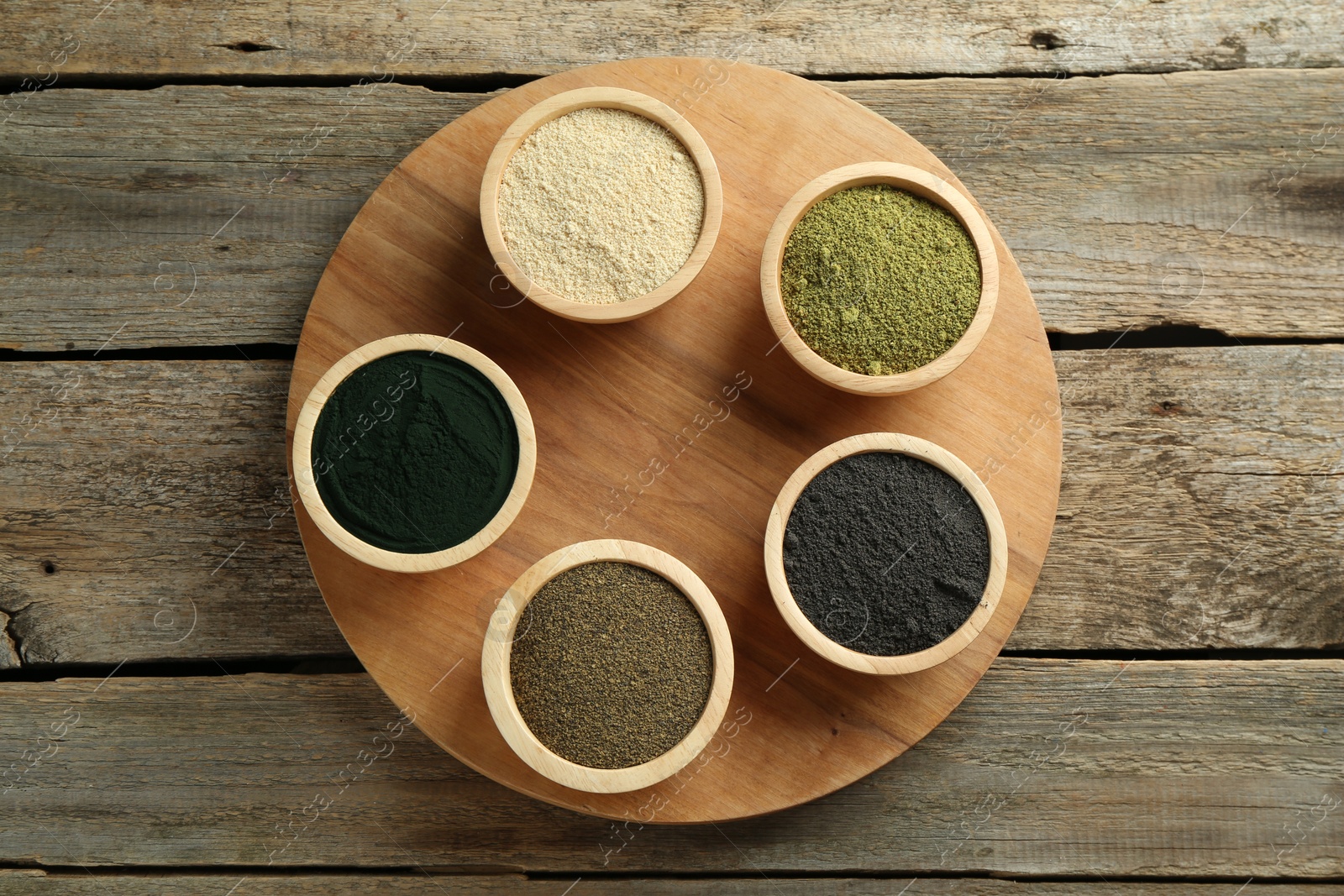 Photo of Different superfood powders in bowls on wooden table, top view