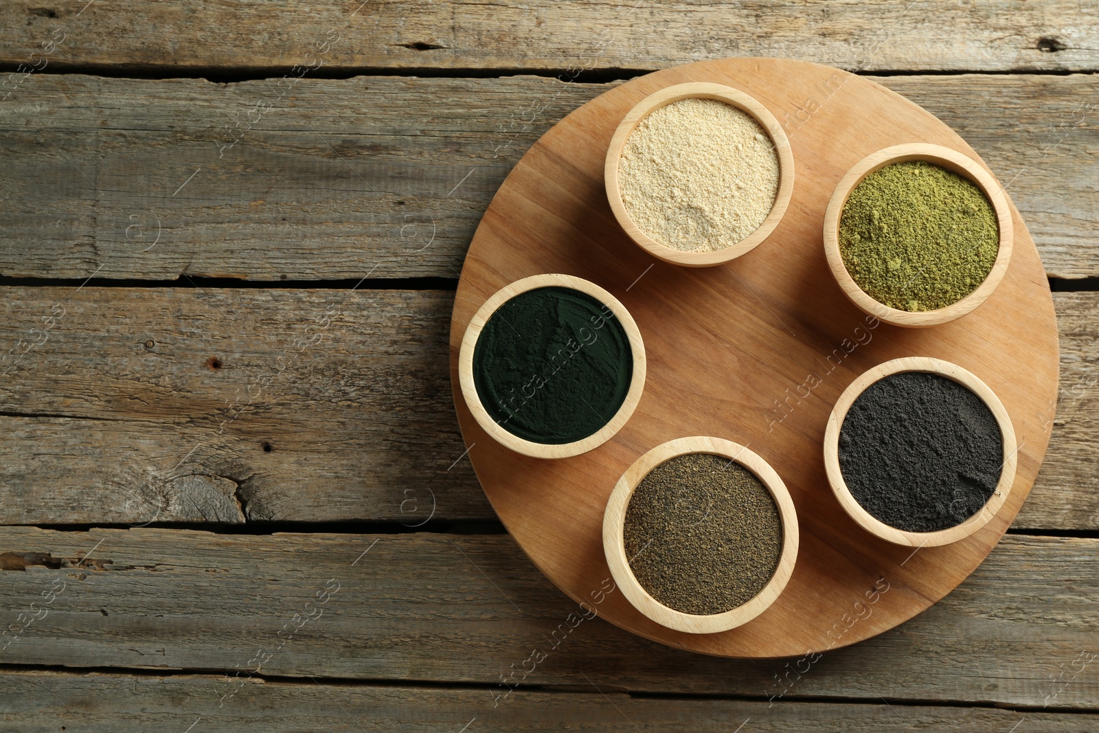 Photo of Different superfood powders in bowls on wooden table, top view. Space for text