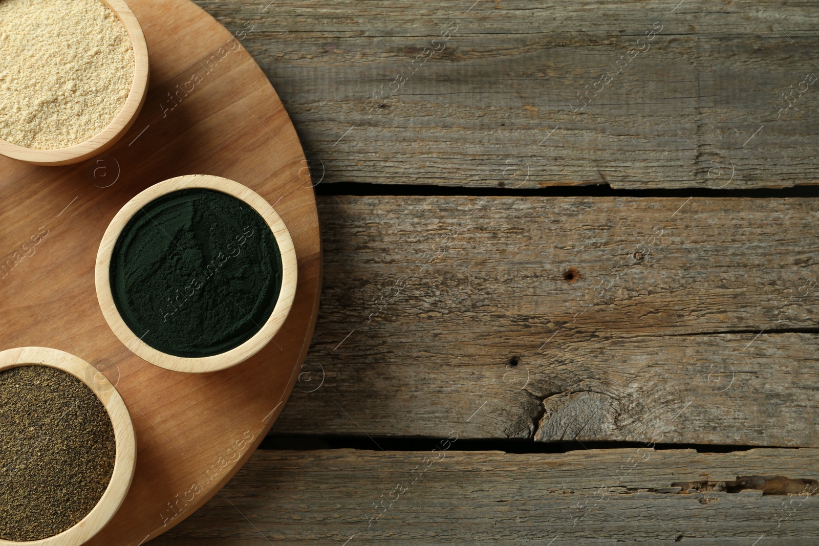 Photo of Different superfood powders in bowls on wooden table, top view. Space for text