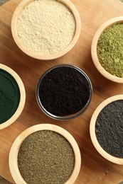 Photo of Different superfood powders in bowls on table, flat lay