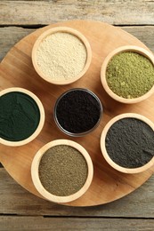 Different superfood powders in bowls on wooden table, top view