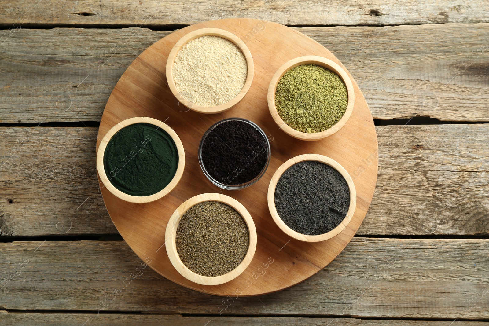 Photo of Different superfood powders in bowls on wooden table, top view