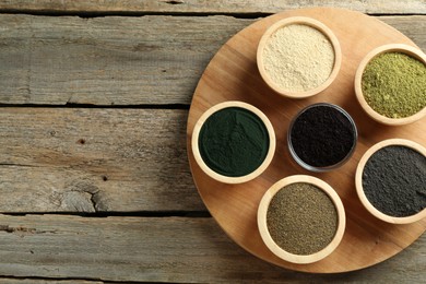 Photo of Different superfood powders in bowls on wooden table, top view. Space for text