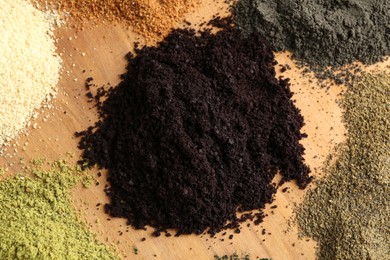 Different superfood powders on wooden table, closeup