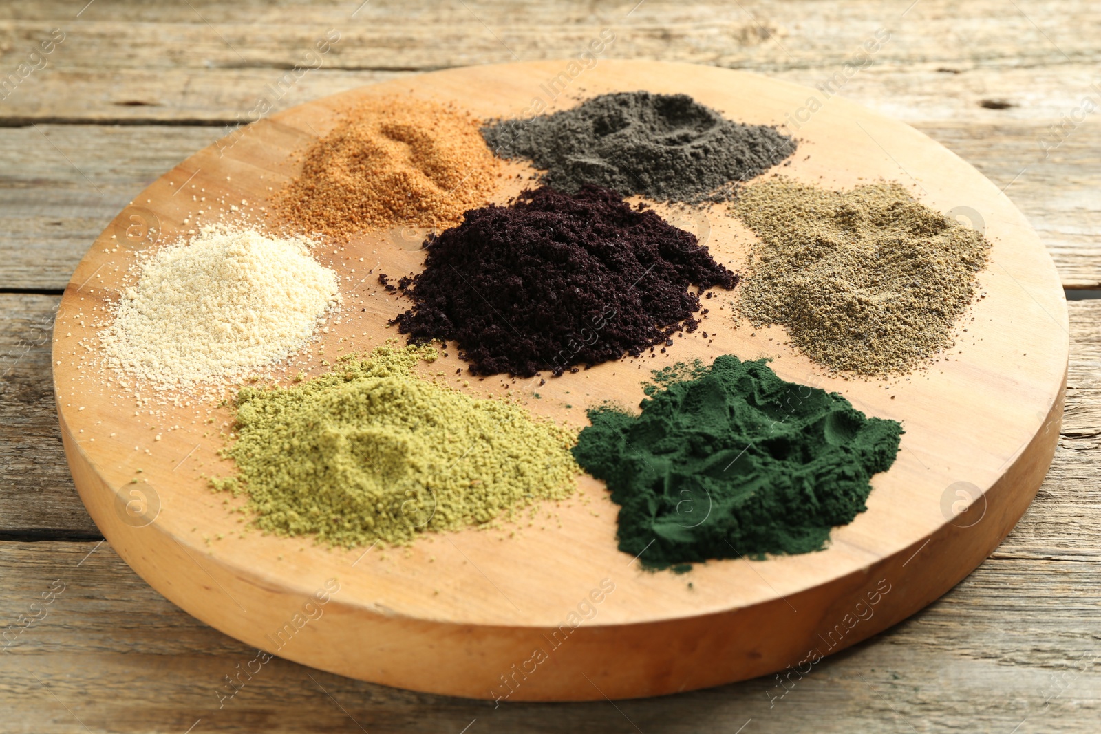 Photo of Different superfood powders on wooden table, closeup